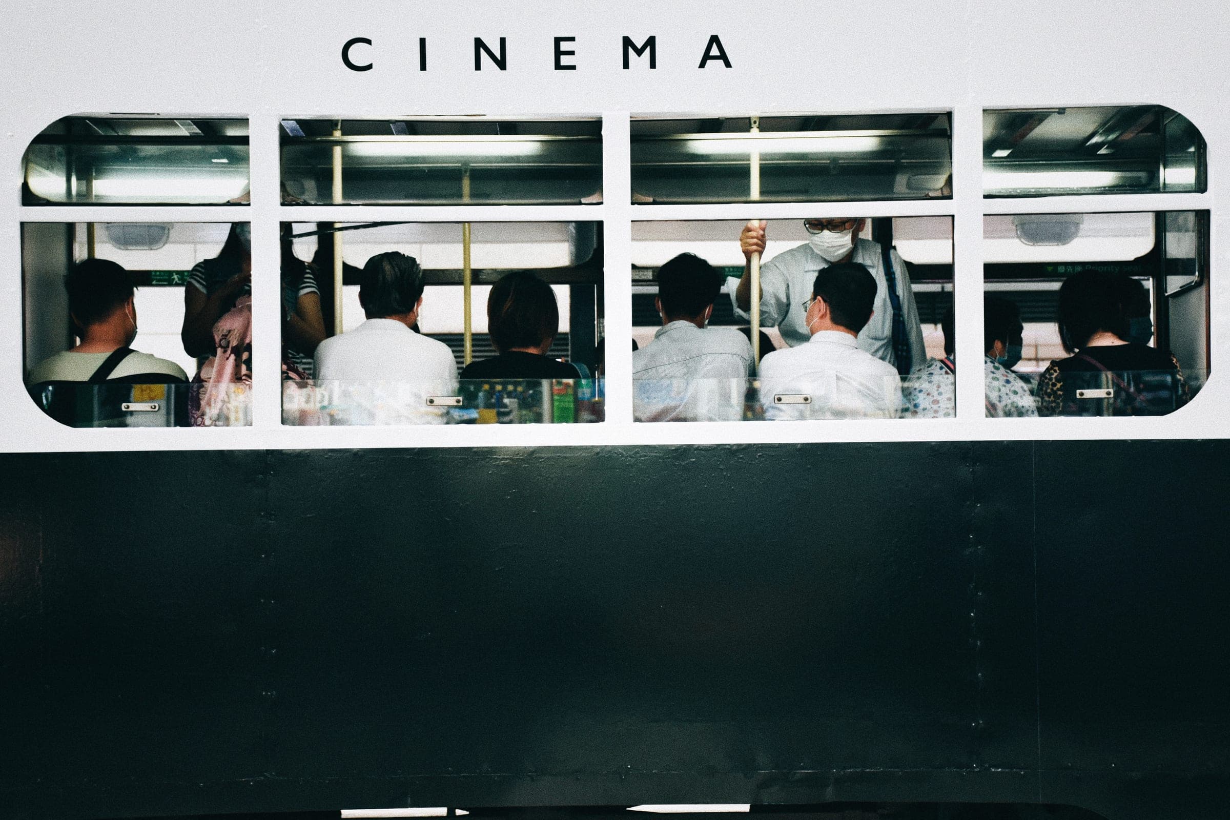 香港電車車廂,車身頂部印有「CINEMA」戲院廣告,乘客企喺車入面